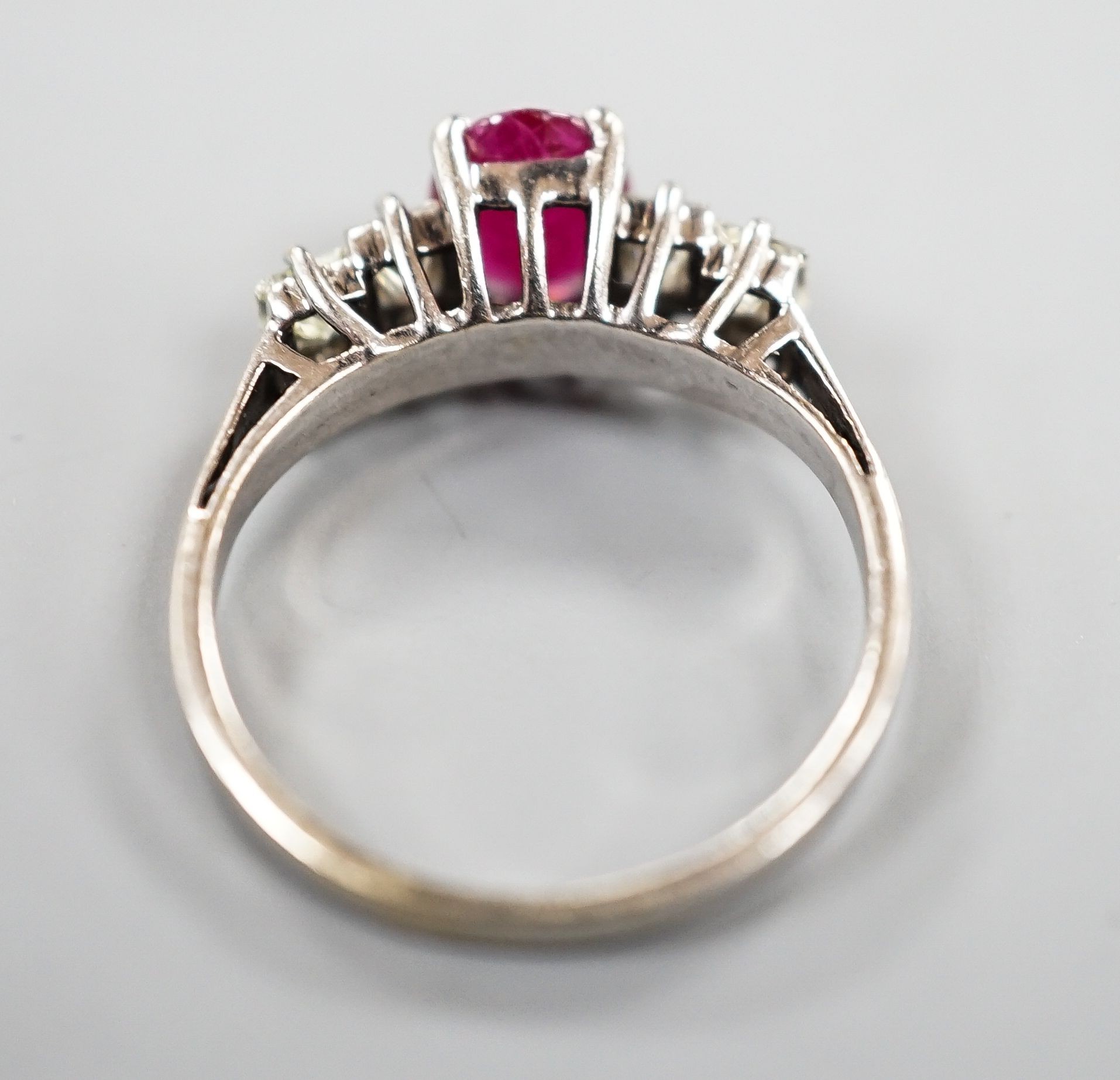 A modern 750 white metal single stone ruby and four stone princess cut diamond set half hoop ring, size M, gross weight 3.2 grams.